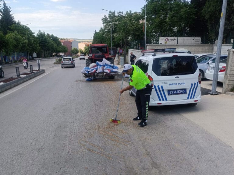 Polis, traktörden düşerek yola saçılan kuzu yemlerini topladı